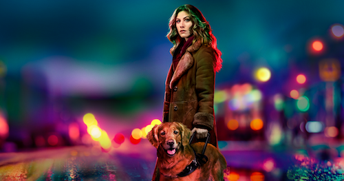 A woman with a golden retriever looks out somberly from a background of blurred, colorful city lights.