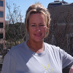 A woman in a Lightning Laces running shirt smiles at the camera.