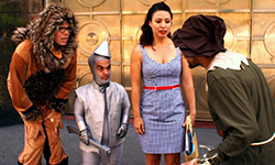 People dressed as variations of the Lion, the Tin Woman, and Dorothy from the Wizard of Oz stare with varying levels of dismay at a piecemeal ScareCrow.