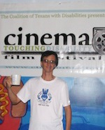 William raises his mug in a toast in front on the Cinema Touching Disability banner