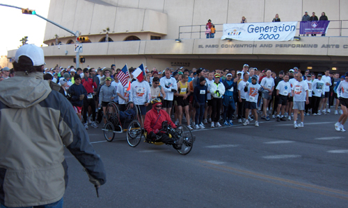 A crowd of people stand behind hand-cyclist